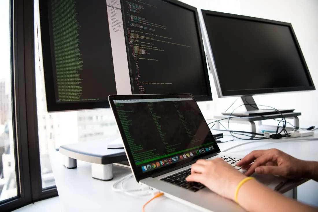 IT support specialist monitoring systems on multiple screens